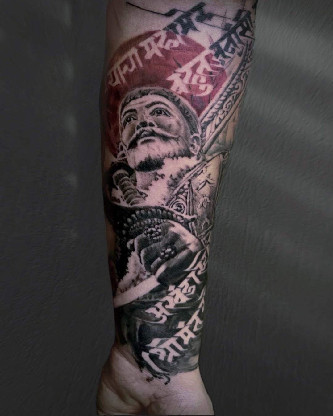A forearm tattoo of Chatrapati Shivaji Maharaj featuring an intricate portrait, bold Marathi script, and vibrant red highlights.